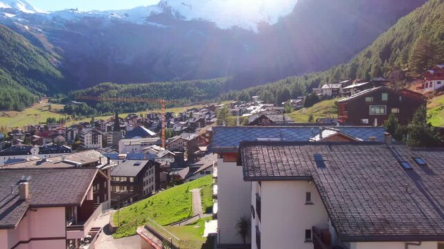 Golden sun rays over a traditional Swiss mountain village surrounded by alpine peaks and forests
