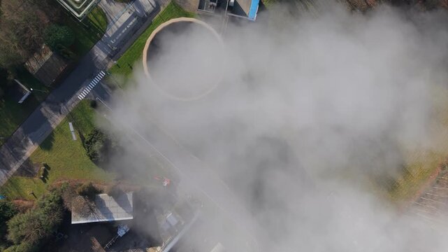 Aerial view of a waste-to-energy plant with steam rising from cooling tower
