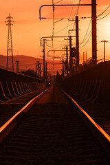 夕焼けに染まる線路と架線柱のシルエット　鉄道インフラの情景