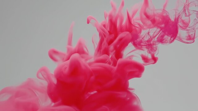 Swirling pink ink erupts in a gray background. Flowing shapes create a beautiful pattern
