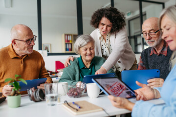 Obraz premium Volunteer teaching seniors how to recognize fake news on digital tablet.