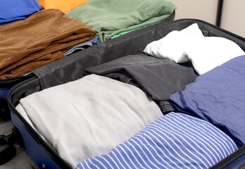 Open suitcase, neatly folded clothes arranged in tidy sections. Organized garments and apparel fill
