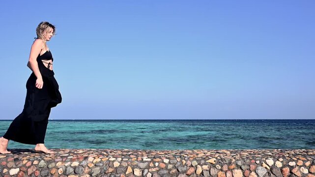 Woman in Black Dress Dances Slowly by the Ocean Under Clear Sky During Summer Holiday in Africa