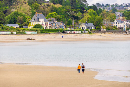 Coastal village on the French coast in Brittany with a couple walking on the beach