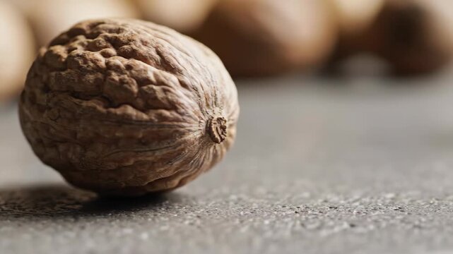 Close up of whole walnuts on textured surface in natural light.