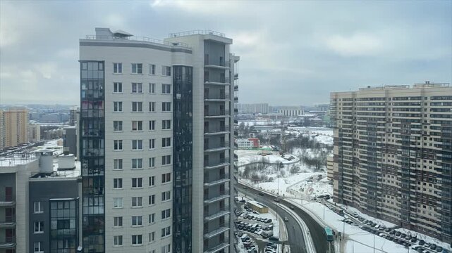 Fast-moving clouds, vehicles, and construction equipment filmed in winter weather in a residential area of ​​the city in time-lapse mode.