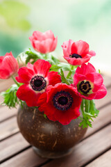 Elegant bouquet of red anemone flowers arranged in a rustic vase, creating a natural and romantic still life ideal for floral, home decor, and botanical themes.