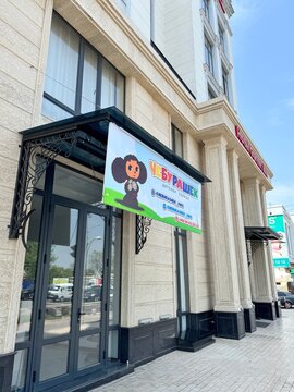 Children's clothing store entrance with grammatically incorrect Russian name Cheburashek and cartoon character in Tashkent, Uzbekistan, April 2024