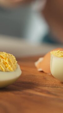 Woman Slicing Hard-boiled Egg In Half With A Knife. - closeup, vertical shot