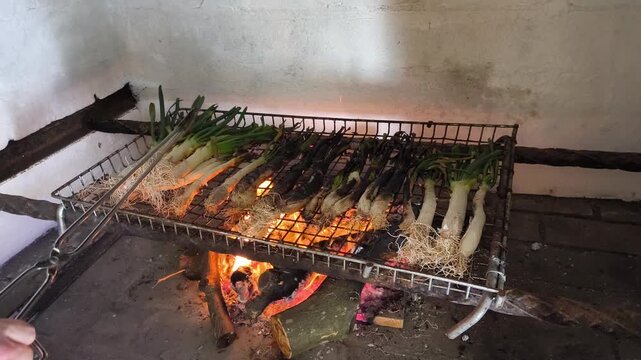 Hands turning cal&ccedil;ots on open fire during outdoor Mediterranean barbecue