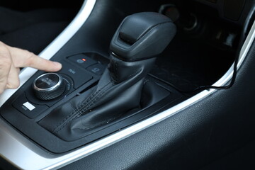 Male hand poin finger pressing drive mode selector button inside car interior
