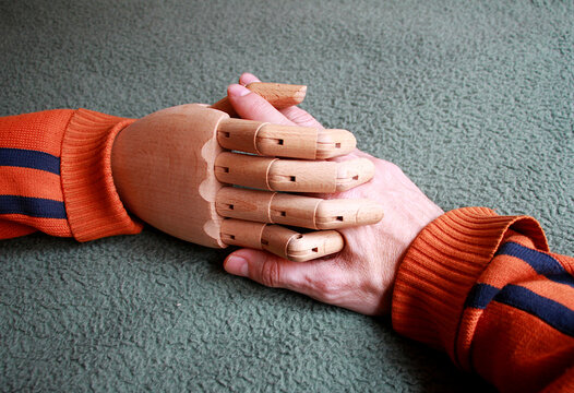 Dando la mano de humano a mano de madera articulada con conexi&oacute;n y uni&oacute;n entre robot aut&oacute;mata y persona de piel y hueso que necesita ayuda