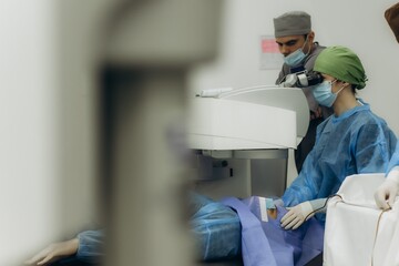 Surgeons performing eye laser correction surgery on patient