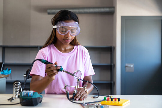 Young woman soldering electronics in a technology workshop