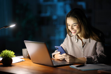Happy tele worker in the night working using phone