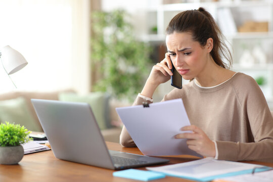 Confused tele worker talking on phone about paper report