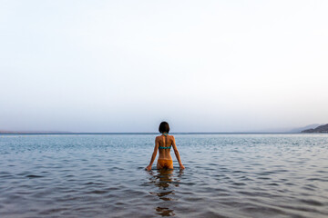 Obraz premium Slender girl in a swimsuit enjoys swimming in the sea. The girl relaxes and swims in the waters of the Red Sea in Israel.
