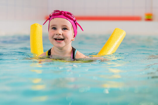Toddler enjoying swimming lesson in an indoor pool.