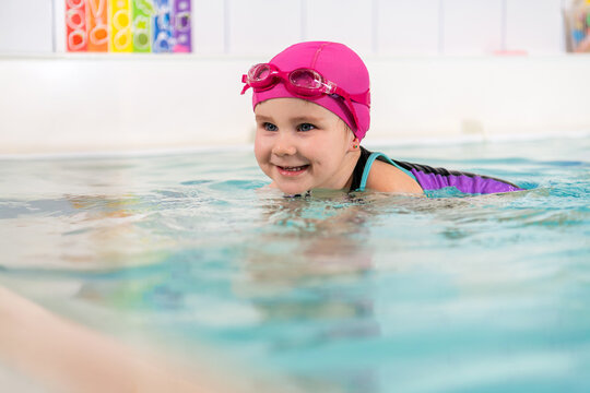 toddler enjoys a swimming lesson in an indoor pool.