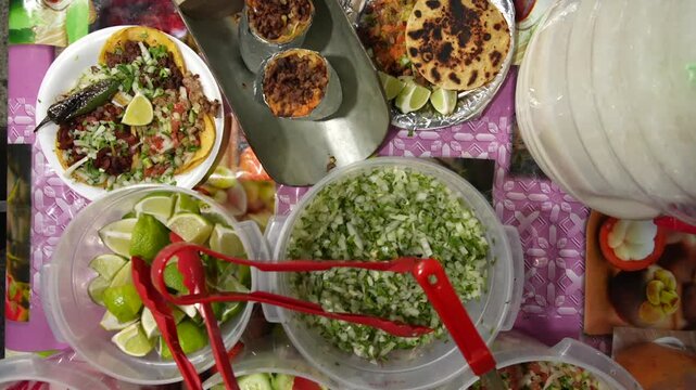 Top-down view of large Mexican burritos surrounded by fresh fillings, sauces, spices, and condiments on a street-style table. Highlights hearty portions, texture, and authentic street cuisine.
