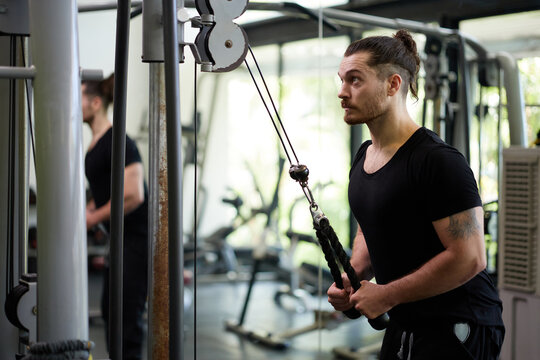 Young sports man workout with rope pushdown in the gym