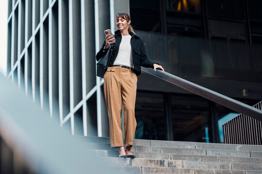 Entrepreneur walking outdoors in city checking mobile phone