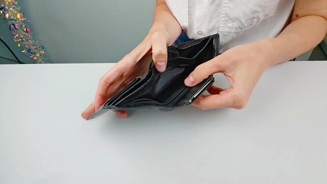 Young woman checking empty wallet at home &ndash; financial struggle, no money, unemployment problem, real life hardship, everyday reality