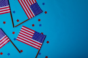 America flag sticks with star shape confetti by copy space on blue background