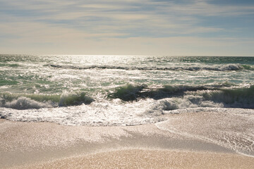Obraz premium Scenic view of waves crashing on shore at beach against sky during sunny day