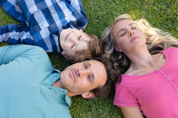 Fototapeta premium Overhead view of caucasian family lying together in the garden