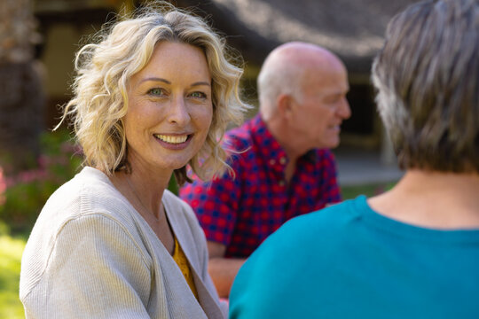 Portrait of blond senior caucasian woman sitting with family in the garden