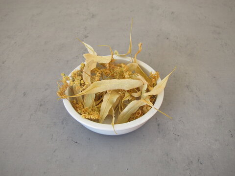 Dried lime blossoms for healing tea in a porcelain bowl