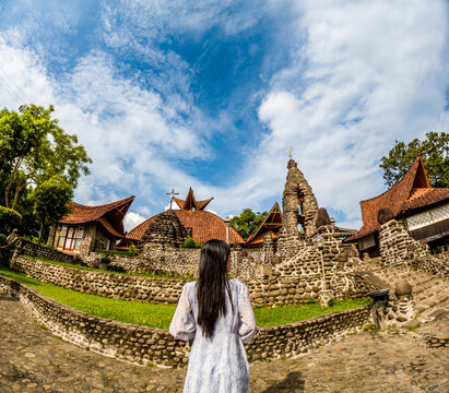 An Asian woman is alone in the poh sarang church. The church has stone walls.