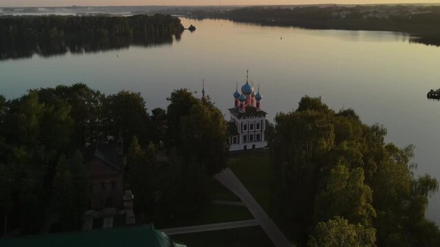 Aerial drone shot of the Church of Demetrius on the Blood in the Uglich Kremlin. Flight over the red facade and union domes against the flow of the Volga River