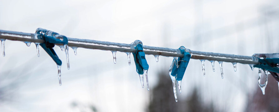 Clothespins covered in ice on a frozen laundry line winter freezing rain concept.