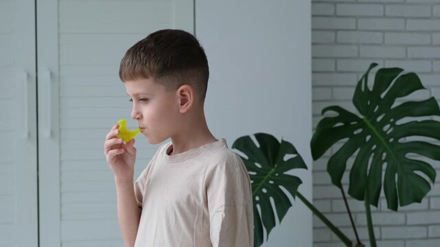 A boy blows into a plastic bird filled with water, making bird sounds.

