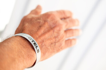 Obraz premium male hand wearing gray hotel wristband, identification band, travel concept, identification bracelet guests, tourism and hospitality industry detail, vacation lifestyle, bar service, all inclusive