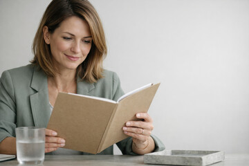Woman reading book at table with glass of water in casual setting
