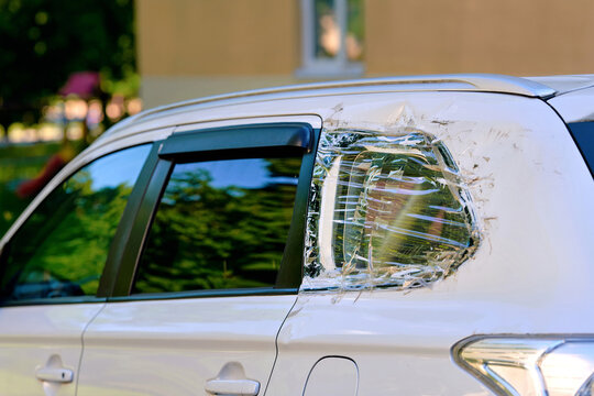 Damaged vehicle rear window. White car with broken rear quarter window that has been temporarily fixed using layers of clear adhesive tape, plastic film following an accident or vandalism. Diy repair