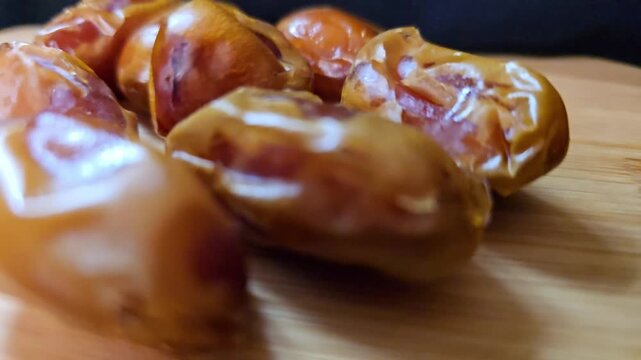 A high-quality macro video showcasing premium Saudi Khalas dates, capturing their natural sheen and rich caramel-colored skin.