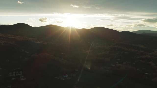 Aerial view of the undulating landscape basking in golden sunlight, casting shadows across the hills of Ascain, Nouvelle-Aquitaine, France.