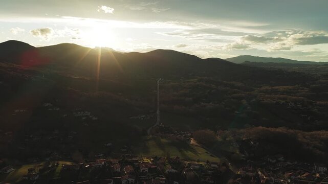 Aerial view of the landscape featuring a road, mountains, and greenery, beautifully lit by the sun's rays in Ascain, Nouvelle-Aquitaine, France.