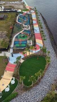 Aerial view of vibrant riverfront park with winding colorful paths, lush green spaces, and recreational areas, Jacksonville, Florida, United States.