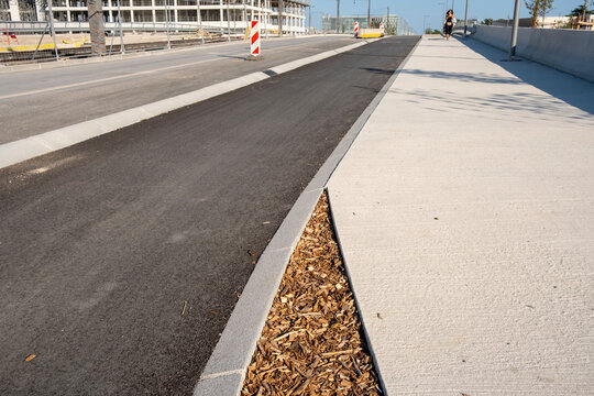 Empty urban street with road asphalt sidewalk and curb leading in perspective lines through a construction area with clean modern infrastructure