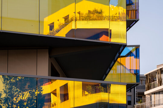 Yellow glass facade on modern architecture building with angular geometric design and sharp reflection creating bold contemporary exterior pattern