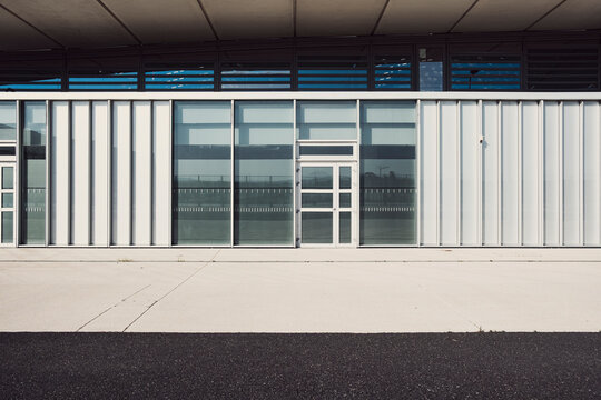 Industrial building facade with metal door and window in minimal design where hard lines and deep shadow define an urban exterior
