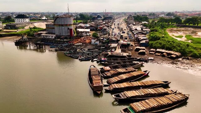 Aerial view of boats near the riverbanks and traffic on the road, with buildings scattered around Iwofe, Port Harcourt, Rivers State, Nigeria.