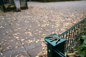 House keys resting on a garden fence in autumn. Everyday outdoor scene showing a personal item, representing routine, mobility, and seasonal life.