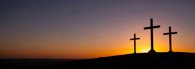 Three Christian crosses on a hill with a dramatic sunset or sunrise sky. religious symbol for Good Friday and Easter concept. Banner with copy space