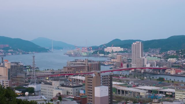 Nagasaki, Japan. Aerial timelapse made from a hill in Nagasaki, Japan, with a view over the entire center, including the bay and the hills. Cloudy and sunny morning in summer, zoom in